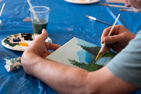 a photograph of someone painting a landscape with mountains and trees