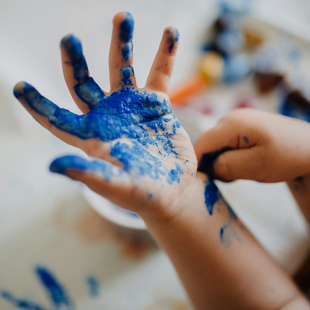 A child's hand covered in blue paint