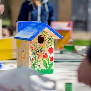 a wooden birdhouse with a blue roof and flowers painted on the front