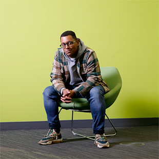 Harrison Mooney sitting in a chair with a green wall in the background