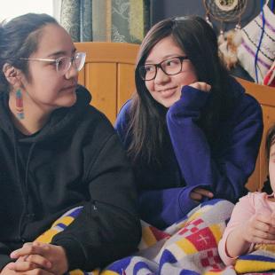 Indigenous youth sitting and looking at each other, smiling