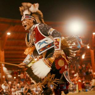 Photograph still from a film of Indigenous dancer wearing ceremonial attire